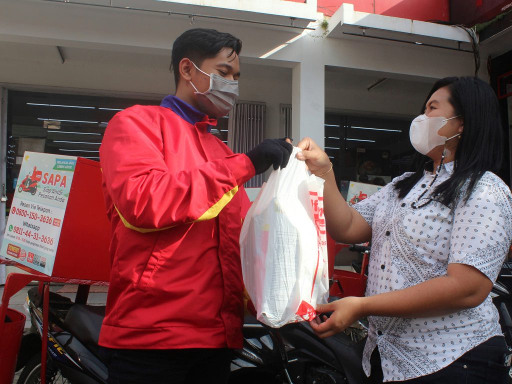 Petugas Alfamart saat mengantarkan belanjaan pembeli.